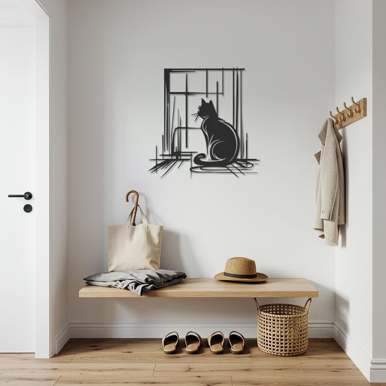 May include: A black metal cat silhouette wall art piece. The cat is sitting in front of a window with a minimalist design. The artwork is mounted on a white wall in a hallway setting. A wooden bench with accessories is below the artwork.