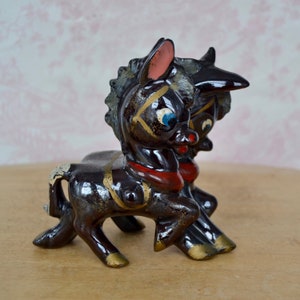 Peut inclure: Deux figurines de donkey en céramique noire avec des accents dorés et rouges. Les ânes se font face et ont de grands yeux peints.