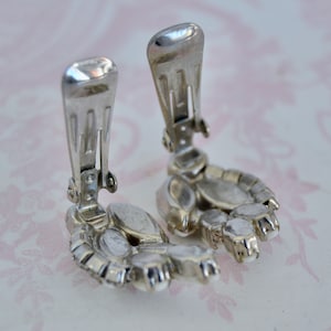 May include: A pair of silver tone clip-on earrings with a cluster of clear rhinestones.