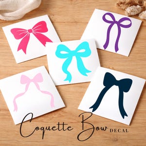 May include: Five white square decals with bow designs in pink, light blue, purple, navy, and light pink. The text "Coquette Bow DECAL" is written in black script at the bottom of the image. The bows are a simple, elegant design.