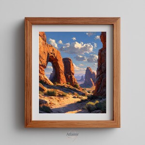 May include: A framed landscape print featuring a desert canyon scene with red rock formations and a natural arch. The artwork depicts a path leading into the distance under a blue sky with fluffy white clouds. The frame is made of light brown wood.