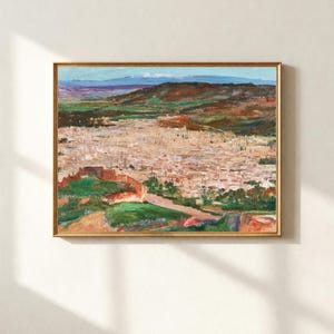 May include: An oil painting in a gold frame depicts a cityscape with a mountain range in the background. The artwork features a palette of greens, browns, and whites, with a focus on the architectural details of the city and the natural landscape.