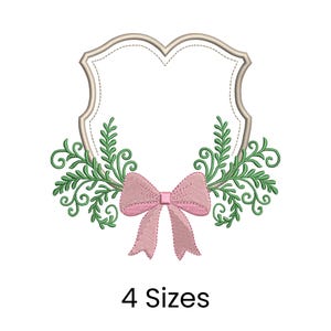 May include: An embroidered design featuring a decorative shield shape with a dotted outline, adorned with green leafy branches and a pink bow. The text "4 Sizes" is displayed below the design.