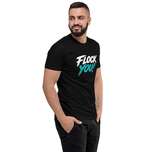 Puede incluir: Una camiseta negra de manga corta con el texto FLOCK YOU! impreso en el pecho. La palabra FLOCK está en blanco y la palabra YOU! en un color verde azulado brillante. La fuente tiene un aspecto desgastado con estilo de pincelada.