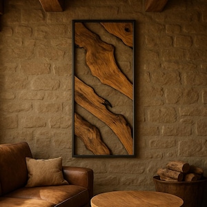 Op de afbeelding: Een rechthoekig houten wandkunstwerk met een zwart frame. Het kunstwerk toont natuurlijke houten elementen in bruin- en beigetinten tegen een achtergrond met textuur. Het stuk wordt tentoongesteld in een woonruimte met een rustiek thema met een leren bank en houten meubels.