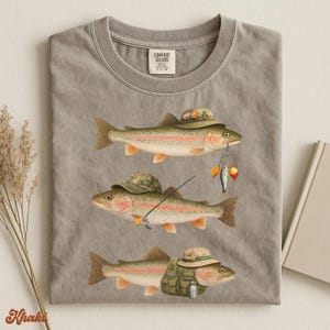 Khaki Comfort Colors® flat lay shirt with three rainbow trout illustrated in full fisherman attire: camo hat, gear vest, and fishing rod.