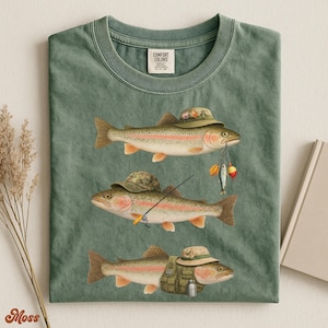 Moss green Comfort Colors® t-shirt laid flat, printed with three trout wearing fishing hats and gear like bait, lures, and vest.