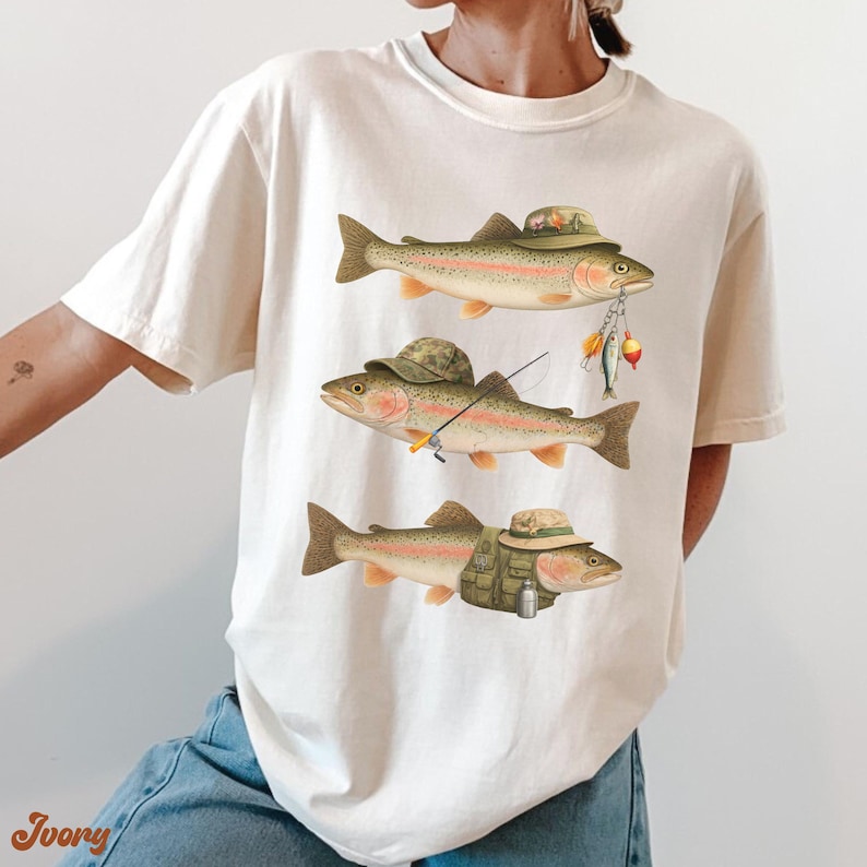 Woman wearing ivory Comfort Colors® tee with three rainbow trout in funny fisherman outfits, including hats, fishing rod, and lures.