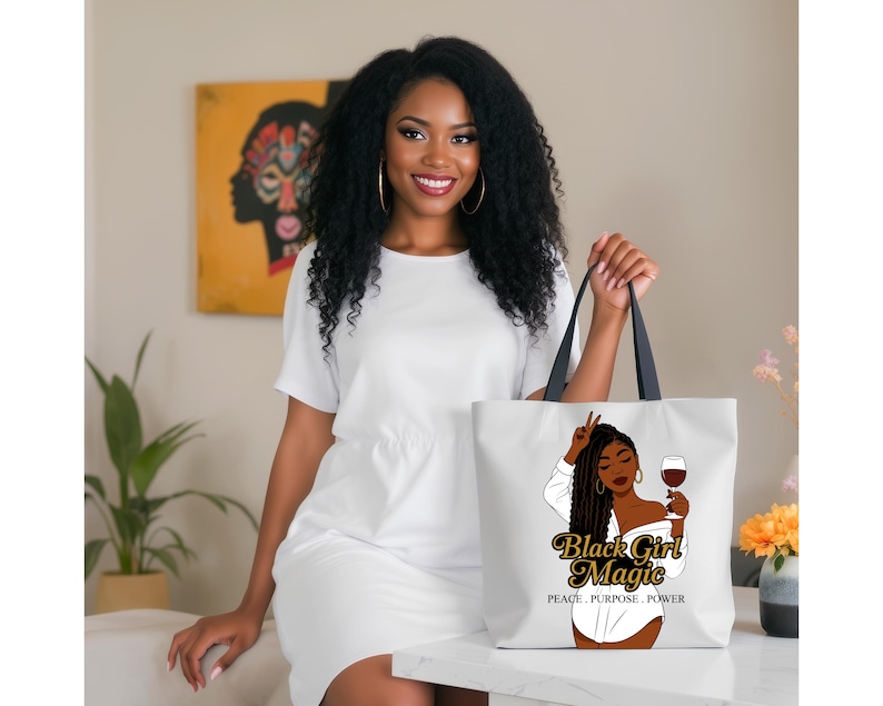 Puede incluir: Un bolso tote blanco con asas negras. Presenta un gr&aacute;fico de una mujer negra sosteniendo una copa de vino y haciendo el signo de la paz. El texto "Black Girl Magic" y "Peace, Purpose, Power" tambi&eacute;n est&aacute; impreso.