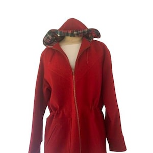 May include: A red hooded coat with a plaid-lined hood. The coat features a zip closure, two front pockets, and a drawstring waist. The coat is displayed on a mannequin against a white background.