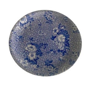 May include: Round ceramic plate with a blue floral pattern on a gray background. The plate features a detailed design of various flowers and foliage, creating a vintage aesthetic. The plate is suitable for serving food.