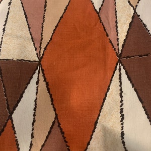 Peut inclure: Un tissu avec un motif g&eacute;om&eacute;trique de triangles bruns, orange, roses et blancs. Le tissu a une surface textur&eacute;e.