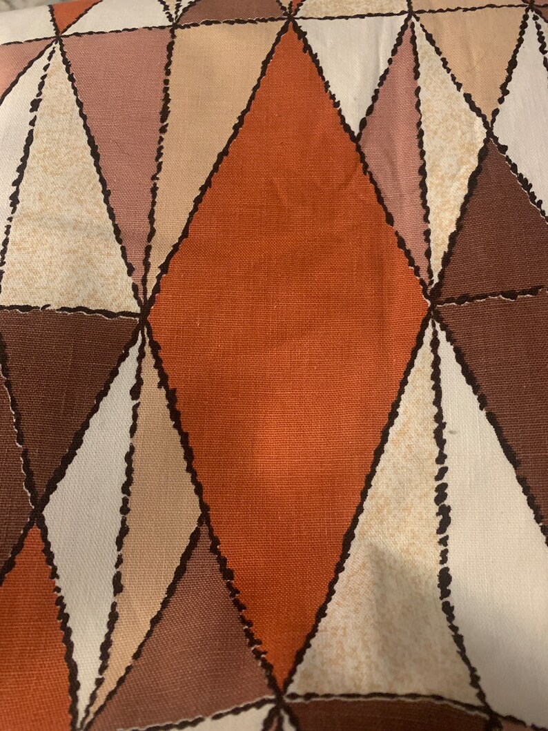 Peut inclure: Un tissu avec un motif g&eacute;om&eacute;trique de triangles bruns, orange, roses et blancs. Le tissu a une surface textur&eacute;e.