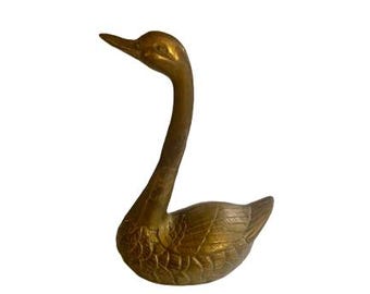 Può includere: Una statuetta di cigno in metallo dorato con collo lungo e piume dettagliate.