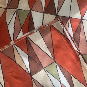 Peut inclure: Un tissu avec un motif g&eacute;om&eacute;trique de triangles dans des tons de brun, orange, vert et blanc. Le tissu a une surface textur&eacute;e.