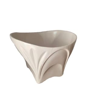 Può includere: Una ciotola decorativa color crema con un design unico e svasato. La ciotola ha una parte superiore ampia e aperta e un esterno scolpito e strutturato. Il design presenta linee verticali curve che creano un aspetto a petalo. La ciotola è in ceramica.