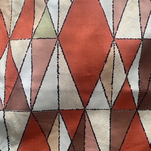 Peut inclure: Tissu g&eacute;om&eacute;trique avec un motif r&eacute;p&eacute;t&eacute; de triangles dans des tons de brun, orange, beige et blanc.
