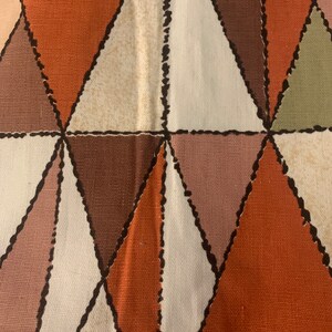 Peut inclure: Un tissu avec un motif g&eacute;om&eacute;trique de triangles bruns, orange, blancs et roses. Les triangles sont soulign&eacute;s de noir et ont un aspect cousu.