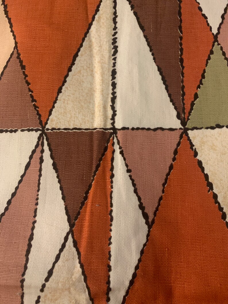 Peut inclure: Un tissu avec un motif g&eacute;om&eacute;trique de triangles bruns, orange, blancs et roses. Les triangles sont soulign&eacute;s de noir et ont un aspect cousu.