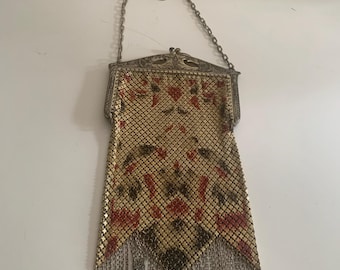 May include: Vintage gold mesh handbag with a silver chain handle and fringe. The bag features a floral pattern in red and black. The metal frame has an ornate design.