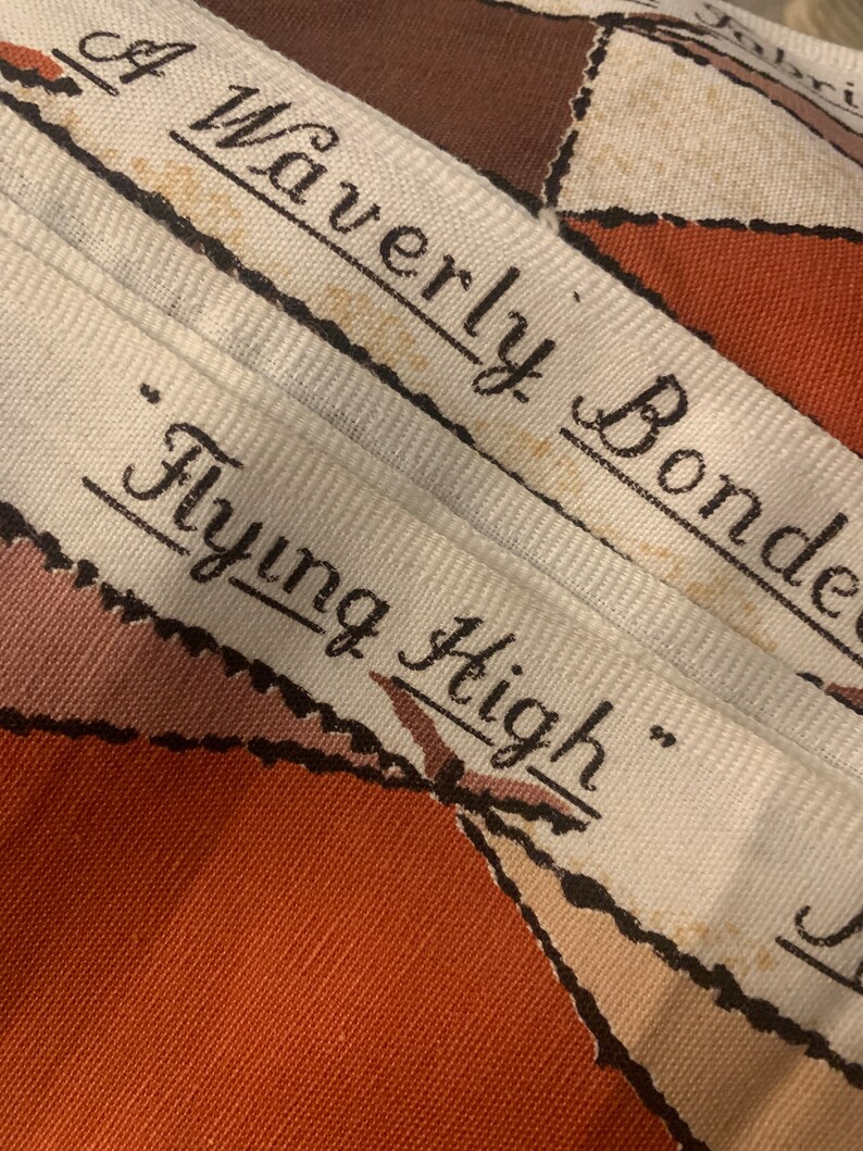 Peut inclure: Une &eacute;tiquette en tissu blanc avec du texte noir qui dit "Waverly Bonded "Flying High" ". L'&eacute;tiquette est sur un tissu &agrave; motifs brun et blanc.