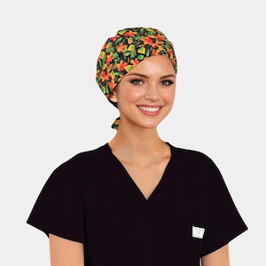 May include: A black scrub top with a V-neck and a patterned scrub cap. The cap features a colorful autumn leaf design in shades of orange, yellow, and green on a black background. The scrub top has a small white tag.