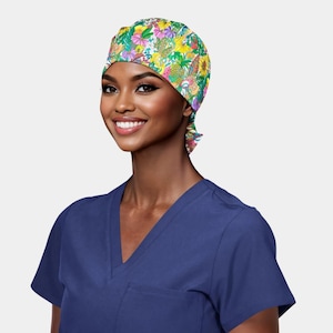 May include: A colorful floral patterned surgical scrub cap. The cap features a vibrant mix of yellow, pink, green, and white flowers and leaves. The cap is tied at the back. The person is wearing a navy blue v-neck scrub top.