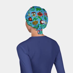 May include: A light blue surgical scrub cap with a colorful floral pattern. The cap features red, yellow, and purple flowers with green leaves. The cap is tied at the back and has a small white tag.