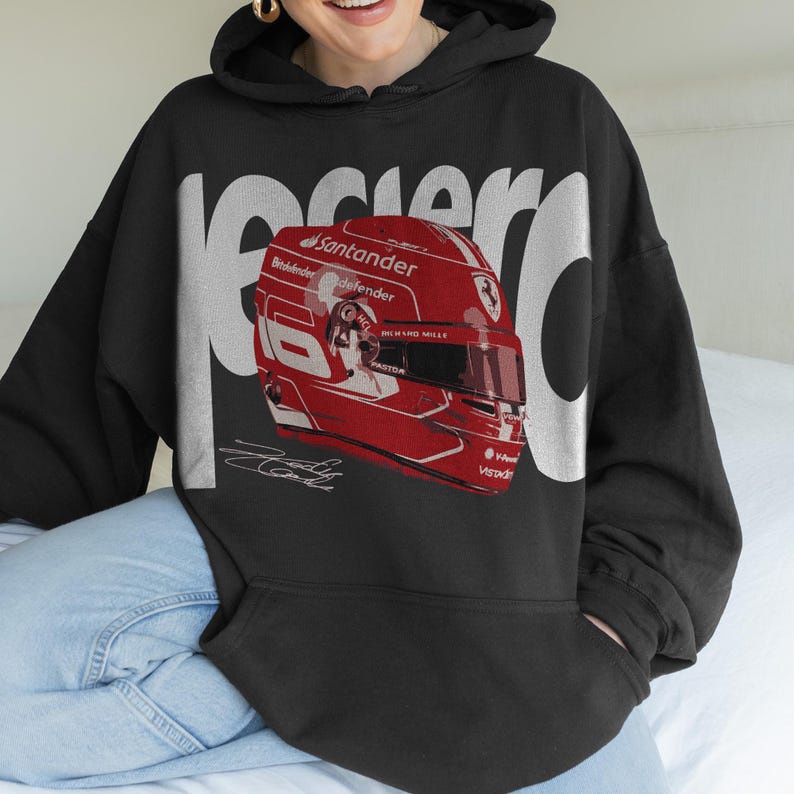 May include: Black hoodie featuring a red racing helmet graphic with the number 16 and sponsor logos. The word "Racer" is printed in large white letters. A signature is printed below the helmet.