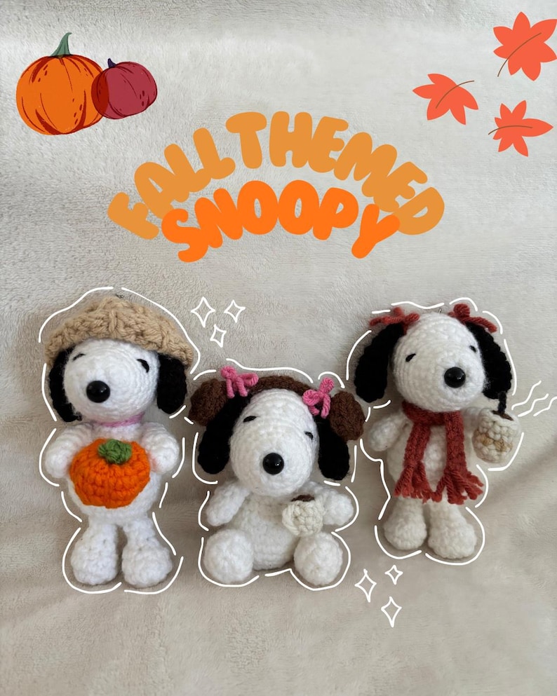 Op de afbeelding: Drie handgemaakte gehaakte Snoopy-poppen in herfstthema's. E&eacute;n houdt een pompoen vast, een ander een kopje koffie en de derde draagt een sjaal. De tekst "FALL THEMED SNOOPY" is oranje. Oranje pompoenen en bladeren zijn ook aanwezig.