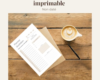 Könnte beinhalten: Ein druckbarer Tagesplaner mit dem Text "Daily Planner | Agenda quotidien imprimable" und "Non daté". Der Planer liegt auf einer Holzoberfläche mit einer Tasse Kaffee und einem Stift.