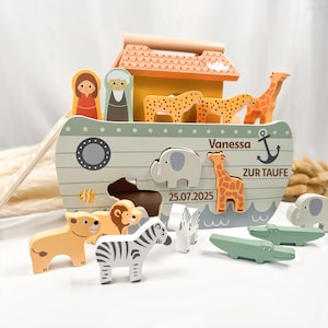 Könnte beinhalten: Ein Holzspielzeug, das die Arche Noah darstellt, mit Tierfiguren wie Giraffen, Zebras und Elefanten. Die Arche ist in Pastellfarben bemalt und trägt den Namen "Vanessa" und das Datum "25.07.2025".