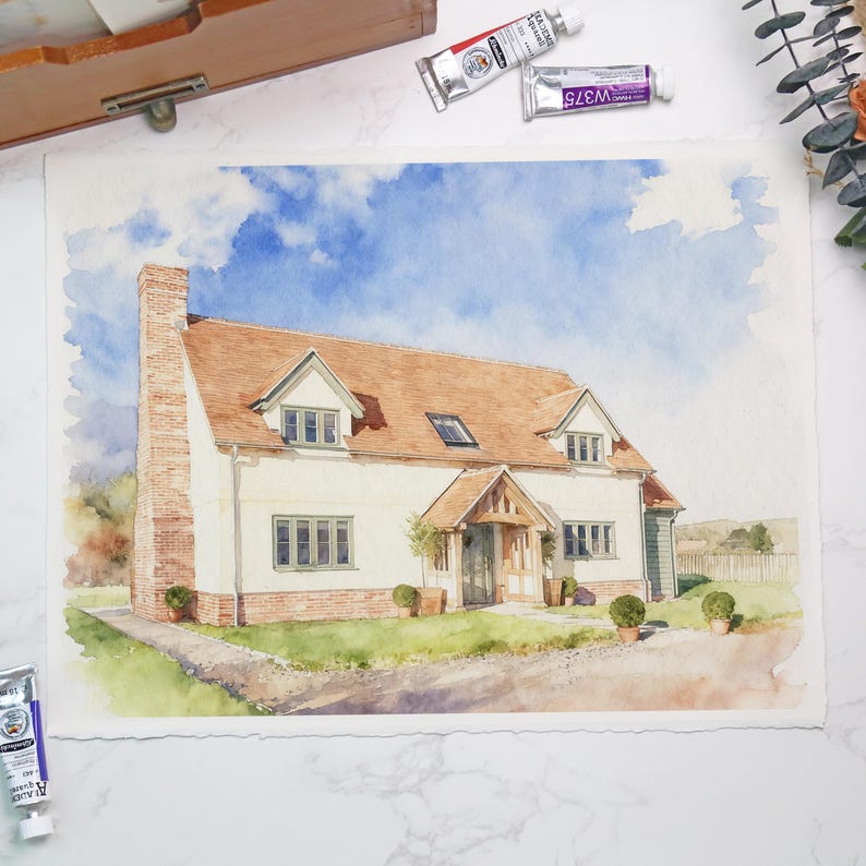 May include: Watercolor painting of a house with a red tile roof, white walls, and a brick chimney. The house has green window frames and a small porch. The sky is blue with fluffy white clouds. Watercolor tubes are in the top left corner.