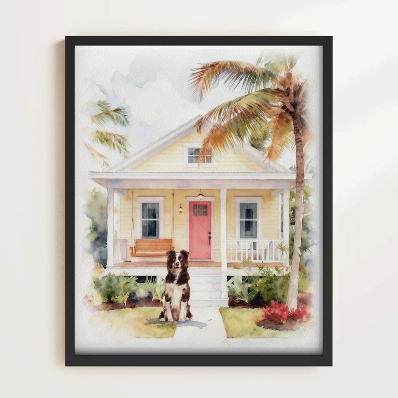 May include: Watercolor print of a yellow house with a pink door, a porch swing, and a palm tree. A brown and white dog sits on the walkway in front of the house. The artwork is framed in a black frame.