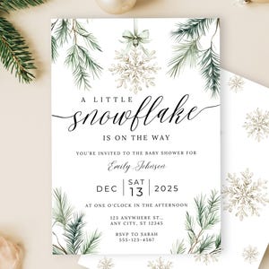 May include: A baby shower invitation with a snowflake theme. The invitation features the text "A Little Snowflake Is On The Way" in elegant script, with watercolor pine branches and a snowflake design. The date is December 13, 2025.