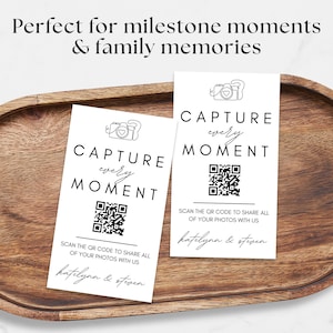 Puede incluir: Dos tarjetas blancas con el texto "CAPTURE every MOMENT" y un c&oacute;digo QR, sobre una bandeja de madera. Las tarjetas tambi&eacute;n incluyen el texto "SCAN THE OR CODE TO SHARE ALL OF YOUR PHOTOS WITH US" y los nombres "katelynn & steven".
