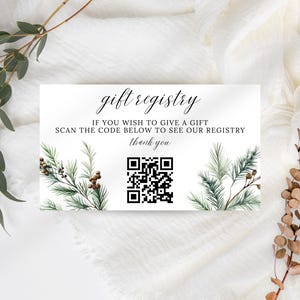 Peut inclure: Une carte blanche pour un registre de cadeaux avec le texte "gift registry" en écriture élégante. La carte comprend le message "Si vous souhaitez faire un cadeau, scannez le code ci-dessous pour voir notre registre, merci." Un code QR est présent.