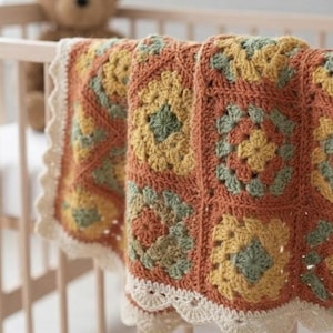May include: A crochet blanket featuring a repeating granny square pattern in shades of terracotta orange, mustard yellow, and sage green. The blanket is finished with a scalloped cream-colored border along the edges, showcasing intricate yarn work.