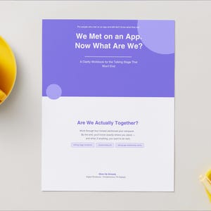 May include: A rectangular workbook titled We Met on an App. Now What Are We? with a purple top half and white bottom half. The text includes A Clarity Workbook for the Talking Stage That Won't End, Are We Actually Together?, and Glow Up Already.