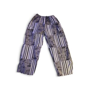 May include: Loose-fitting pants featuring a patchwork design of alternating vertical stripes and panels with a dark gray mushroom and butterfly print. The garment has an elasticized waistband and two side cargo pockets on the upper thighs.