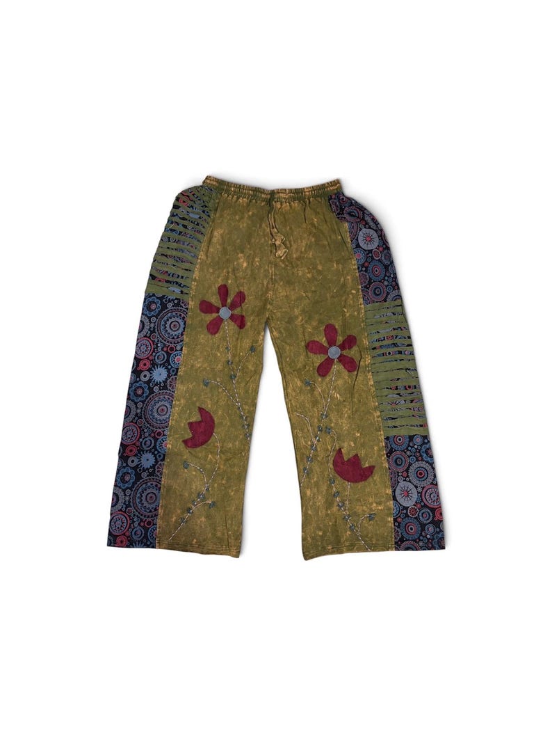 May include: Olive green wide-leg pants featuring a mottled texture, an elastic drawstring waistband, and dark blue side panels with circular patterns. The front displays embroidered red flower motifs with thin stems and light blue accents.