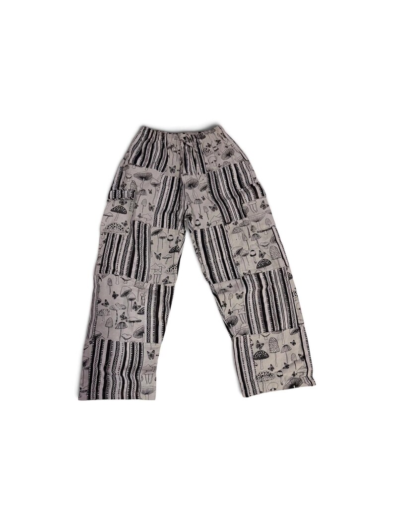 May include: A pair of light gray pants featuring a patchwork design with alternating panels of black and white vertical stripes and a repeating black ink-style print of various mushrooms, small butterflies, and botanical elements throughout.