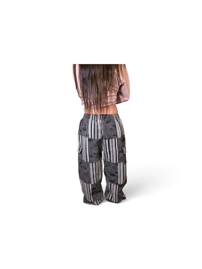 May include: Loose-fitting cargo pants featuring a patchwork design of black and white fabric panels. The pattern alternates between solid black sections with a subtle mushroom print and vertical striped sections. The pants include side cargo pockets.