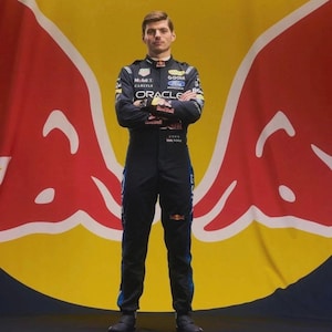 Puede incluir: Un traje de carreras azul marino oscuro con varios logotipos de patrocinadores, incluidos Oracle, Mobil 1 y Ford. El traje tiene cuello alto, mangas largas y un diseño ajustado. El logotipo de Red Bull y el nombre Max aparecen en la parte frontal.