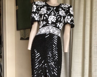 Peut inclure: Une robe noire et blanche à paillettes avec un motif floral. La robe a des manches courtes et une silhouette ajustée.