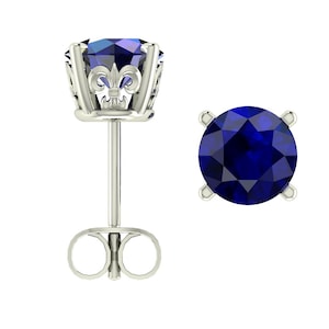 Op de afbeelding: Een paar zilveren oorbelletjes met elk een blauwe saffier-edelsteen. De oorbelletjes hebben een decoratief filigraanontwerp rond de edelsteen.