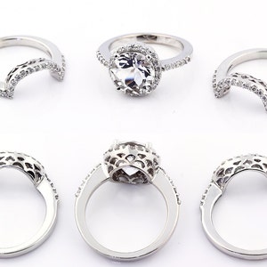 May include: A set of three silver rings with a delicate, intricate design. The rings are adorned with small, sparkling stones. The center ring features a larger, round stone.