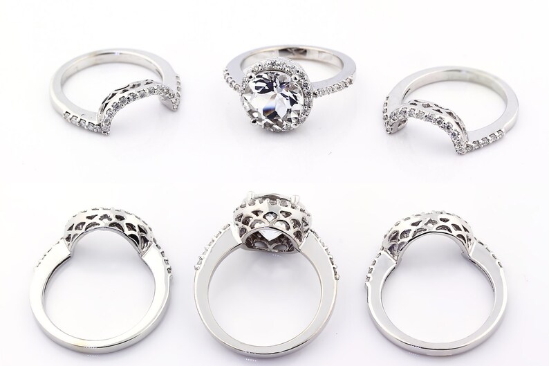 May include: A set of three silver rings with a delicate, intricate design. The rings are adorned with small, sparkling stones. The center ring features a larger, round stone.