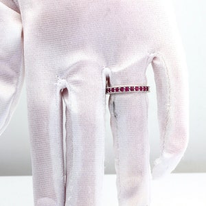 May include: A silver band ring with a row of small, red gemstones.