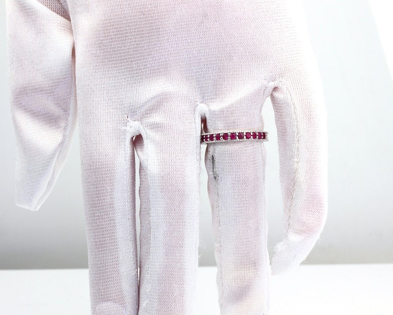 May include: A silver band ring with a row of small, red gemstones.